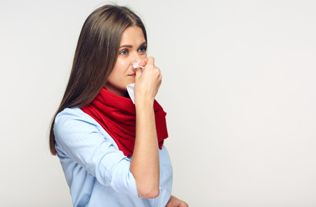 Sickness woman blowing his nose in paper tissue. Isolated on white background illness girl.の写真素材