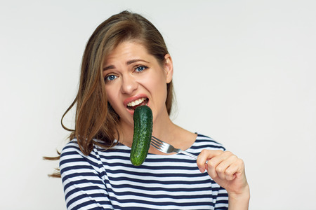 Dieting is not always fun. Isolated portrait of woman holding cucumber on fork.の写真素材