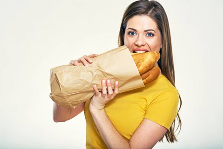 Woman wearing bread from shopping bag. Isolated studio portrait.の写真素材