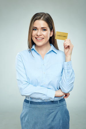 Happy bank emloyee woman holding golden credit card. Isolated studio portrait.の写真素材