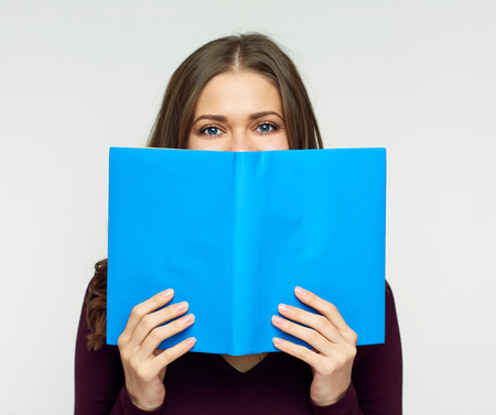 Student girl hid face behind blue book. Isolated portrait.
