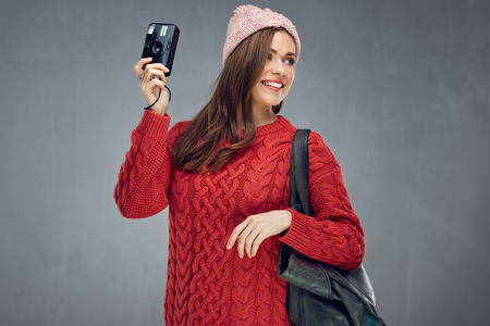 Happy girl tourist holding photo camera. woman traveler portrait on gray wall back.