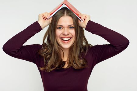 Smiling woman holding book on her head. Isolated portrait.の写真素材