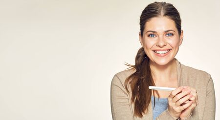 Happy smiling woman holding pregnancy test. isolated female portrait.