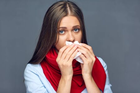 Allergies or flu sickness woman holding paper tissue isolated portrait on gray studio back.の写真素材
