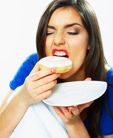 Woman bite donut. Close up portrait of young woman holding plate with donut.の写真素材