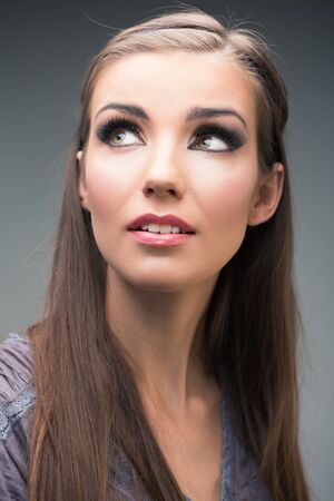 Woman face close up portrait looking up isolated on gray.の写真素材