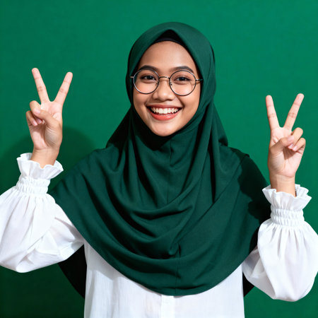 Cheerful Southeast Asian Muslim Woman Showing Peace Sign V Gestureの素材