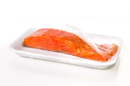 piece of salmon in the packaging from the supermarket on white backgroundの写真素材