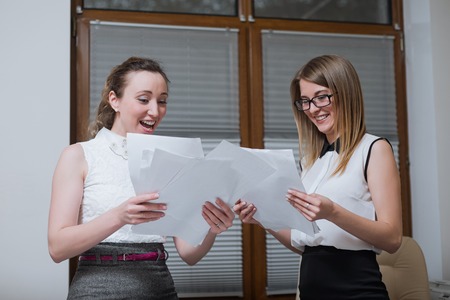 Two women business partners discussing plans or ideas, sitting at a Desk in the office and look through financial statements, statistics and documentsの写真素材