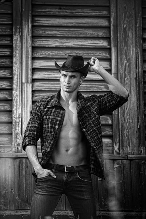 Sexy courageous handsome young cowboy with amazing muscles and abs poses for a photoの写真素材