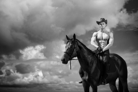 Macho man handsome cowboy and horse on the background of sky and water. Western styleの写真素材