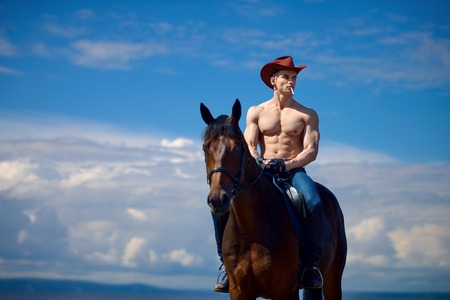 Macho man handsome cowboy and horse on the background of sky and water. Western styleの写真素材