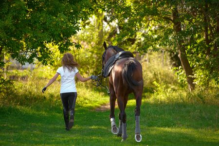 A young girl rider and her horse return to the stable after training.の写真素材
