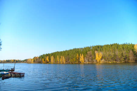 Beautiful autumn landscape with clear blue lake and yellow autumn trees. The sky and autumn yellow...