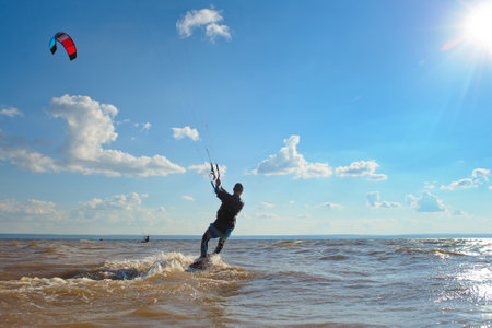 Kiteboarding. A kite surfer rides the waves. A middle-aged man enjoys riding the waves on a kite.の写真素材
