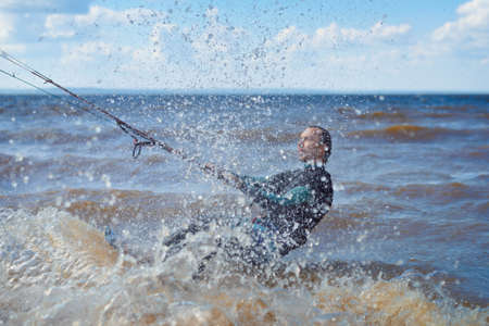 Kiteboarding. A kite surfer rides the waves. A middle-aged man enjoys riding the waves on a kite.の写真素材
