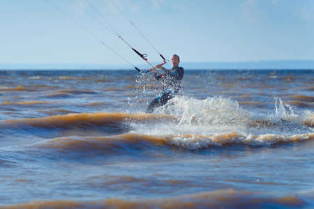 Kiteboarding. A kite surfer rides the waves. A middle-aged man enjoys riding the waves on a kite.