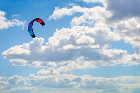 A colorful kite floats in the sky on the background of clouds.