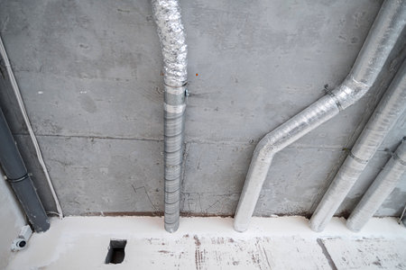 Wiring of ventilation pipes on a concrete ceiling in a house under construction. The room is under...