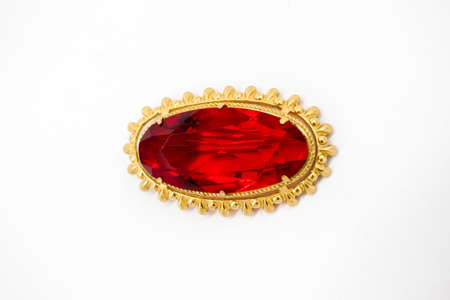 Golden brooch with a ruby ââstone in the middle on an isolated white backgroundの写真素材