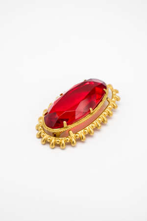 Golden brooch with a ruby ââstone in the middle on an isolated white backgroundの写真素材