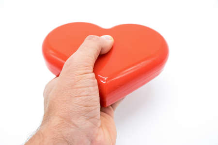 Hand holding red heart on white background