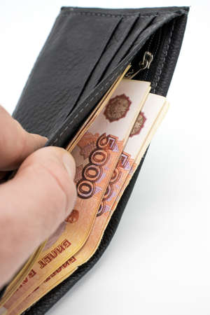 A purse with money on a white background and a hand that counts bills.