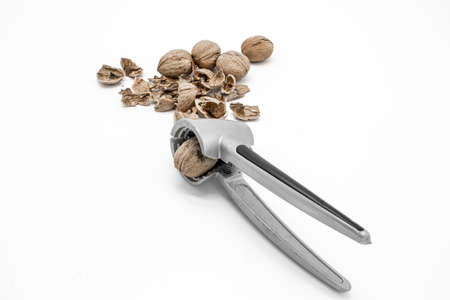 Walnuts on a white background, broken by a nutcrackerの写真素材