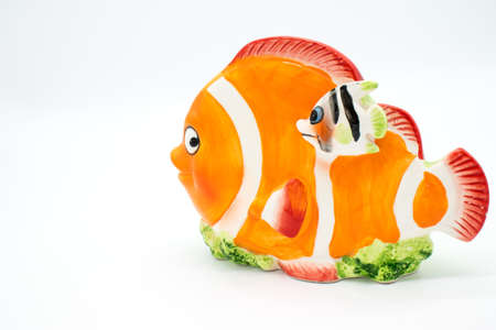 Porcelain piggy bank in the shape of a clown fish on a white backgroundの写真素材