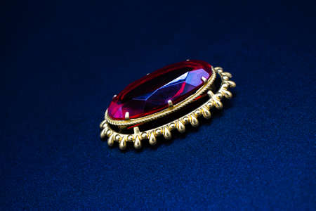 Gold brooch with a ruby ââstone on a dark backgroundの写真素材