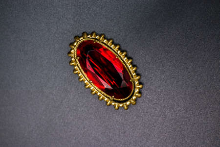 Gold brooch with a ruby ââstone on a dark backgroundの写真素材