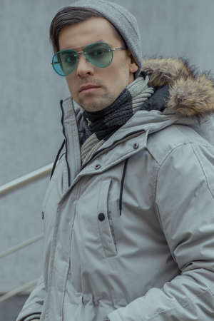 Close-up portrait of a man in turquoise sunglasses and a winter warm jacket