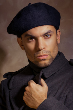 Portrait of a handsome young guy in a beret and a military-style coat