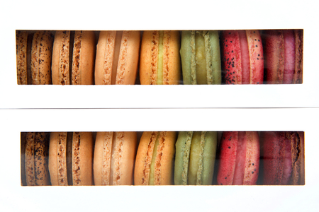 Macaron cookies in white boxes with clear plastic windows showing a display of colorful cookies.の写真素材