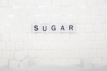 Wall of sugar cubes with word SUGAR spelled out on some of the bricks. sugar delivers âempty caloriesâ  calories unaccompanied by fiber, vitamins, minerals, and other nutrients.の写真素材