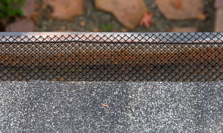 Close up on section of rain gutter on residential home, free of leaves and debri, covered with mesh....