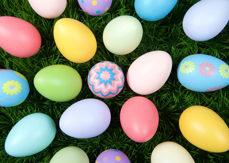 Colorful decorative and plain easter eggs arranged in random circular pattern on green grass. Close up flat view from above.の写真素材