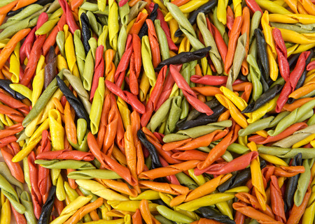 Background of bright colorful hand rolled dry pasta made from vegetables. Healthy vegetarian Italian pastaの写真素材