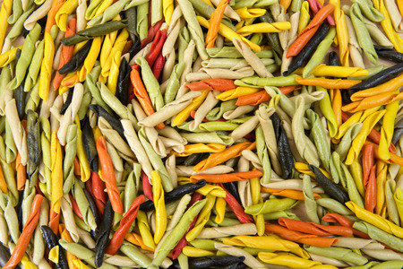 Background of bright colorful hand rolled dry pasta made from vegetables. Healthy vegetarian Italian pastaの写真素材