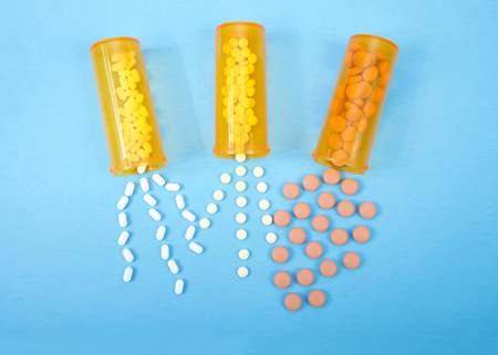 Top view flat lay three medication bottles spilling contents out onto blue background.
