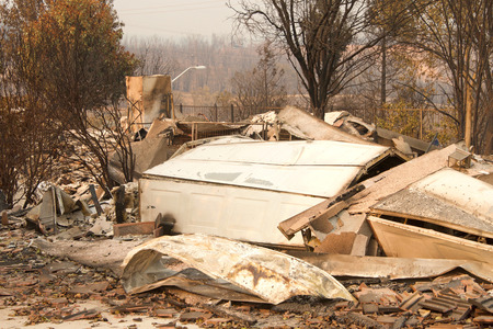 home burned to the ground, garage door buckled and laying in a heap after the recent wild fire fire storm in Redding, CA. Smoke and ash in the air as the fire continues to burn several miles away.の写真素材