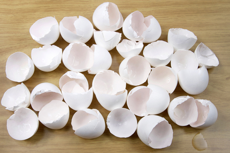 Many broken eggs on a wood table. To make an omelet, you need to break a few eggs. Metaphor for in...