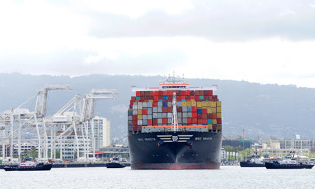 Oakland, CA - May 20, 2019: Multiple tugboats assist cargo ship MSC VANDYA to turn 180 degrees as...