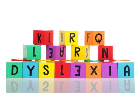 Bright colorful wooden toy blocks stacked on a reflective surface spelling dyslexia. Learning...