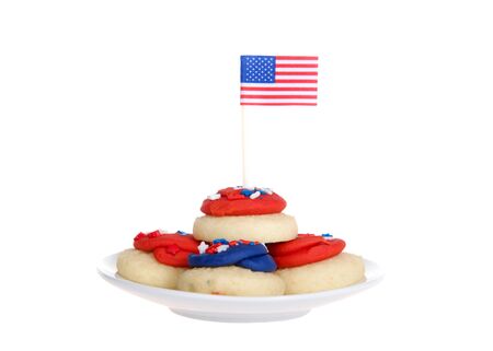 small white porcelain plate with vibrant colorful patriotic bite sized frosted sugar cookies, tiny flag in top cookie. isolated on whiteの写真素材