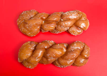 Flat lay top view of two glazed twist cinnamon rolls. Bright red background.