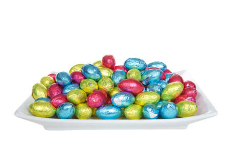 Close up of a rectangular porcelain plate filled with chocolate easter eggs covered with brightly colored foil wrappersの写真素材