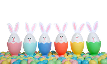 Row of Easter Eggs crafted into bunnies with felt ears, sitting in colorful egg cups with colorful...