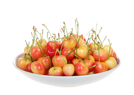 Close up of a porcelain bowl full of fresh organic Rainier Cherries, isolated on a white backgroundの写真素材
